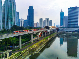 A red and white Jabodebek LRT train travels on a track.