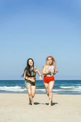 Couple of alternative girls running on the beach on a beach picnic