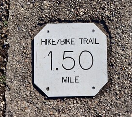 A close view of the silver miles distance sign on the path.