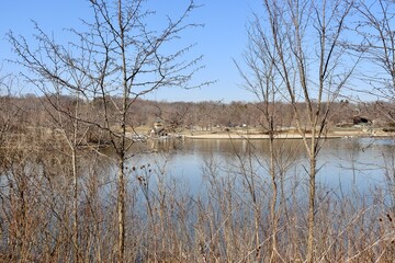 The peaceful lake though the bare trees on the shore.