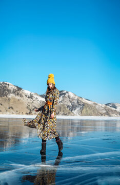 Fashionable image of a stunning woman posing on Baikal Lake ice wearing yellow hat