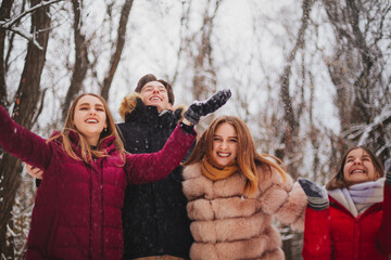 Happy best friends teenagers enjoying cold winter weather and first snow while having fun outdoor
