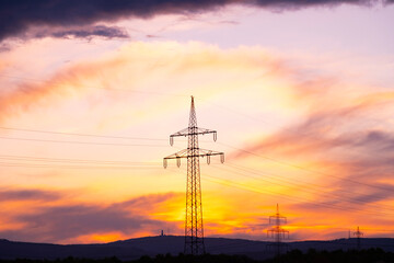 beautiful dramatic landscape, power towers, field in evening in rays of sunset, concept beauty of nature, modern energy, technology, seasonal change of weather