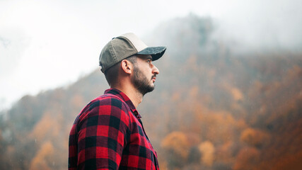 Portrait of Handsome Young Man with Cap and Checkered Shirt in Foggy Autumn Forest