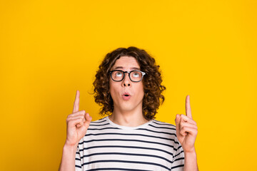 Close up photo of young amazed funny nerd guy direct fingers above head much useful information isolated on yellow color background - obrazy, fototapety, plakaty