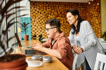 merry inclusive preteen boy with Down syndrome sitting in front of laptop and phone next to his mom