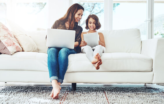 Laptop, tablet and mother with child on sofa for streaming movies, happiness and bonding together in living room. Family, mom and young girl with technology for watching videos, film or relax in home