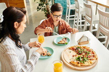 joyous mother eating pizza and drinking juice with her inclusive cute son with Down syndrome