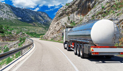 Fuel truck on a picturesque road. A white tank truck transports fuel. - obrazy, fototapety, plakaty