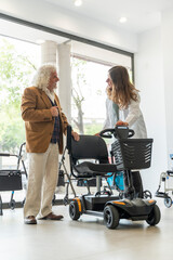 Older man in an orthopedic shop trying out an electric scooter