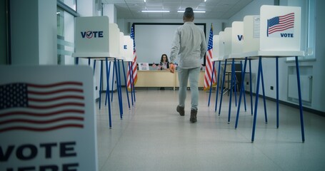 US citizen, African American male voter walks to female polling officer for registration at polling...