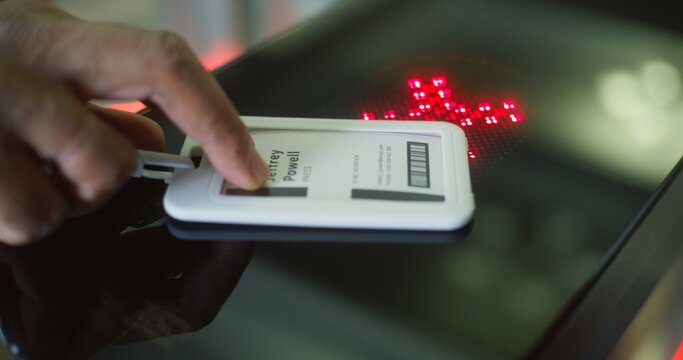 Turnstile with touch panel for automatic identification in modern office building. African American man or businessman uses electronic pass card and passes through gates into the business center.