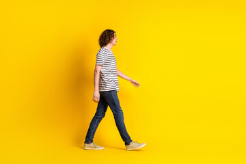 Full size profile portrait of nice young man walk empty space wear striped t-shirt isolated on...