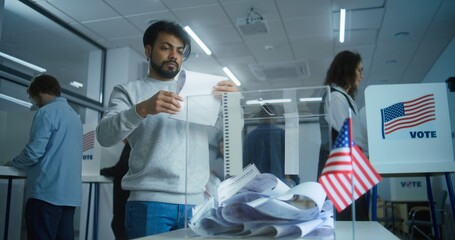 Multicultural voters, US people vote in voting booths at polling station. Indian man puts ballot...