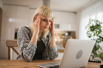 Young woman with headache migraine while she browse internet on laptop