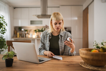 Young woman read instruction for medical browse internet at kitchen