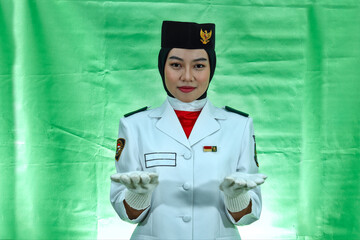 Close up photo young girl Indonesian National Flag Hoisting Troop making gesture like holding something. National Paskibraka Council isolated in green background

