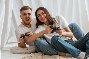 Playing video game with joysticks. Young couple are together at home