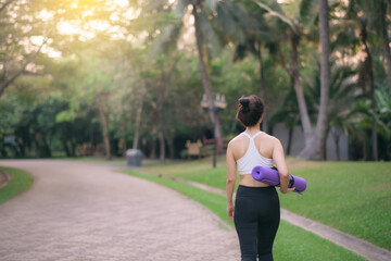 back of fitness yoga woman walking in the park with yoga mat - 788388430