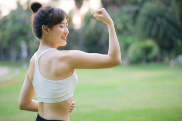 Strong fitness asian woman runner showing off muscular arms flexing biceps. wellbeing success concept. - 788388471