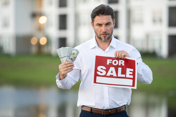a man in a white shirt holding money in his hands. real state agent giving new house key. Estate...