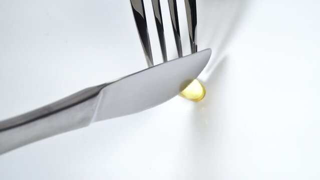 Eat a pill with fork and knife on a white background