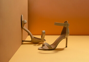Creative idea of women's beige sandals with a high heel placed in the corner. Sustainable fashion...