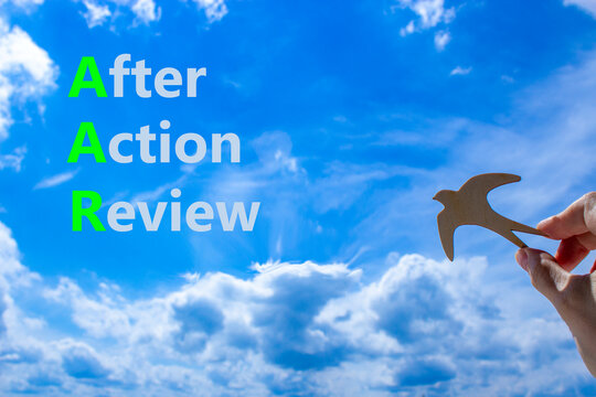 AAR After action review symbol. Concept words AAR After action review on beautiful blue sky clouds background. Wooden bird. Businessman hand. Business AAR after action review concept. Copy space.