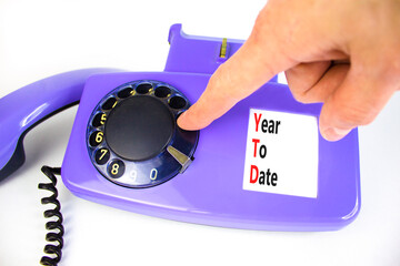 YTD year to date symbol. Concept words YTD year to date on beautiful old disk phone. Beautiful white background. Businessman hand. Business YTD year to date concept. Copy space.