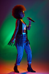 Professional vocalist with stylish afro hair performing jazz songs in neon stage light against...