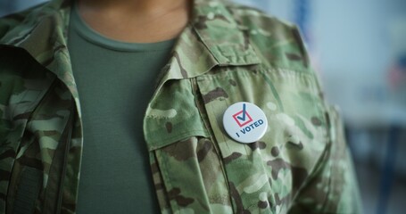 Close up of anonymous military man putting on badge with American flag logo and inscription I Voted. US Army representative at polling station during elections. National Election Day in United States.