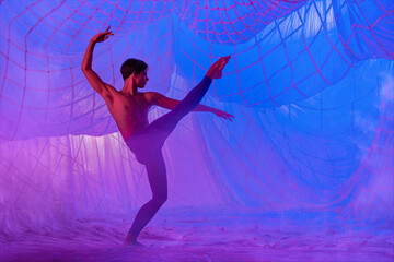 A man in a blue suit dances ballet on a blue background.