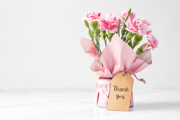Carnation flower bouquet with thank you tag on marble table