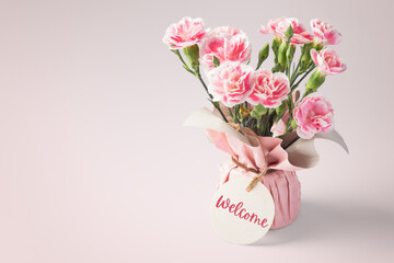 Flower bouquet with welcome tag on vintage pink background