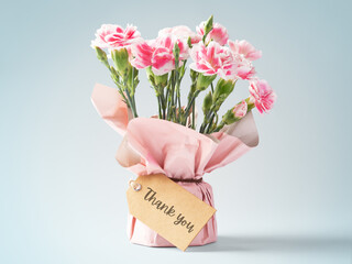 Pink flower bouquet with thank you tag on vintage blue background