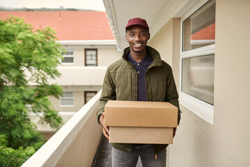 Smiling African delivery man standing outside carrying packages