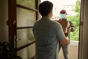 African courier in a mask handing packages to a customer