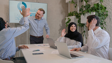 Happy team colleagues celebrate winning business deal achieve victory give high five multiethnic businessmen and muslim businesswoman in hijab working in boardroom office unity partnership teamwork