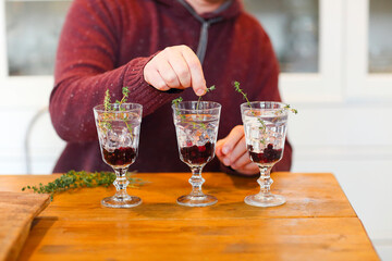 Man decorating elegant wineglasses with herbs