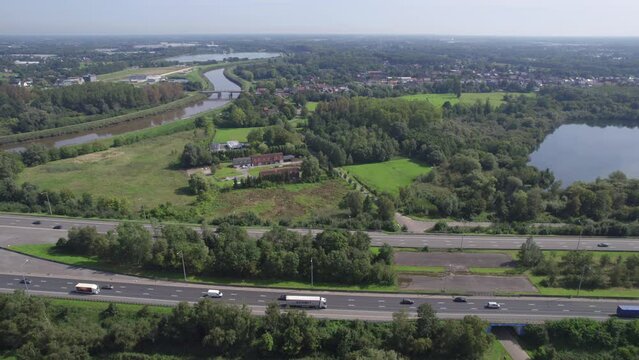 This drone footage presents a stunning bird's-eye view of the E19 highway near Mechelen, Belgium, as it runs through a vibrant tapestry of Belgian landscapes. The scene captures the contrasting yet