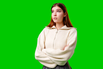 Young Woman With Crossed Arms Looking Thoughtfully to the Side Against Green Background