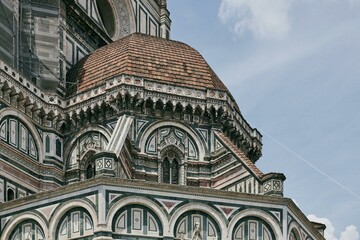 A grand building with a majestic dome crowning its top, against the backdrop of a cloudy sky. The...