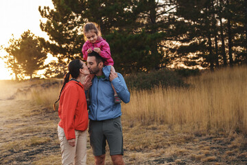 Family enjoys a serene walk in nature - child riding happily on her father’s shoulders - mother...