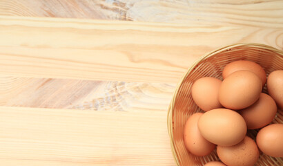 Chicken eggs in a wicker basket, top view. Eggs on a wooden background. Fresh raw eggs. Brown...