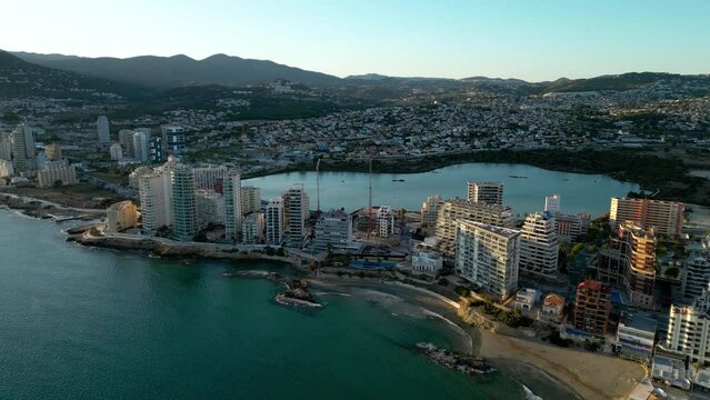 Cinematic aerial view of Calpe city at sunset. Coastline with skyscrapers. Warm colours reflecting on building and landscape. Famous travel destination in Alicante, Spain. Drone going forward.