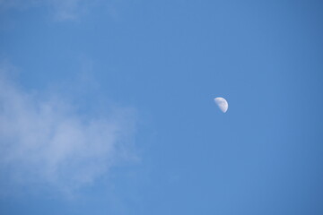 A view of the moon with a blue sky with some clouds. le Croisic, France - April 16, 2024.