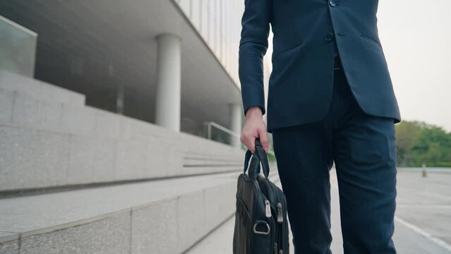 Mid Body shot of Businessman walking and look at wrist watch for the time, city walking path next to glass office building, smart formal clothes urban commuter, salesman going out for work