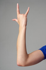 Female hand sign against gray background in studio