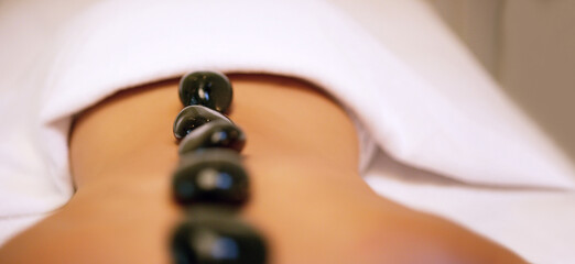 Spa, treatment and rock on back for woman, stress relief and pain or muscle tension help. Relax,...