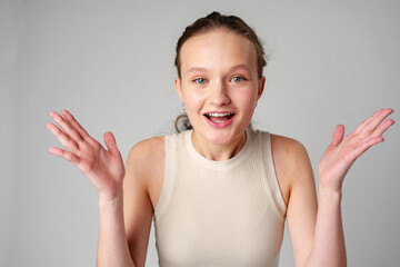 Young Clueless Woman Standing With Outstretched Arms on gray background